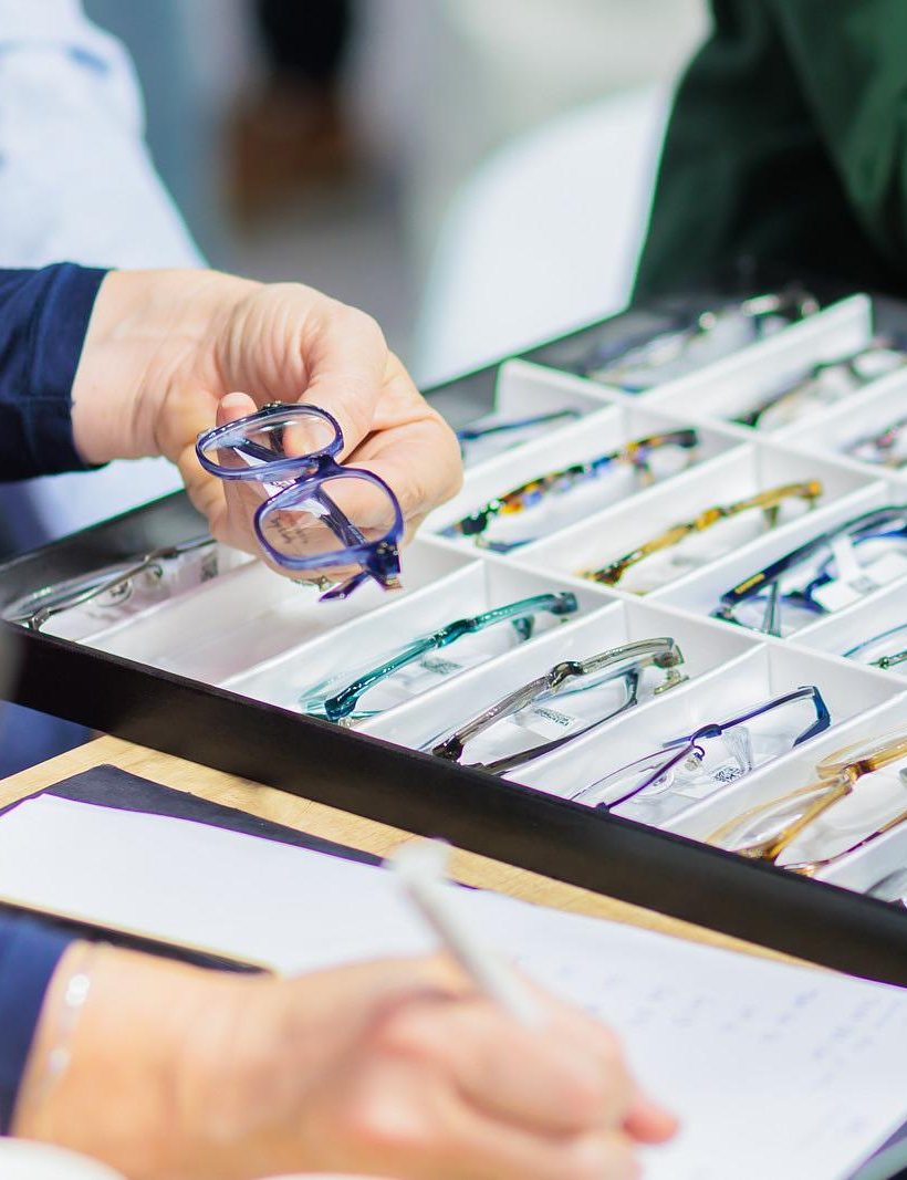A hand holds a frame above a tray of samples while another hand takes notes on a sheet.